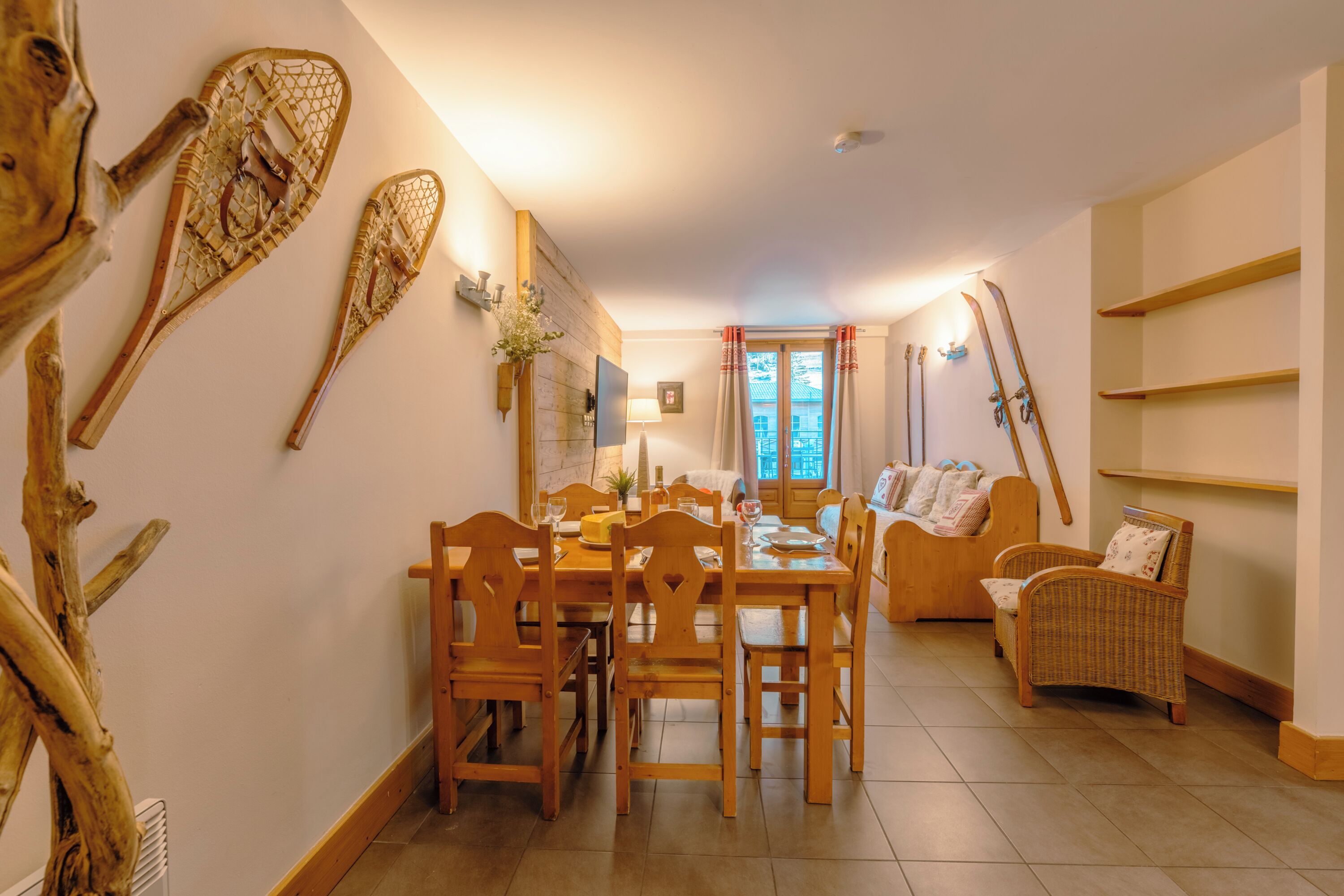 A dining area with wooden furniture, a fireplace, and skis leaning against the wall.