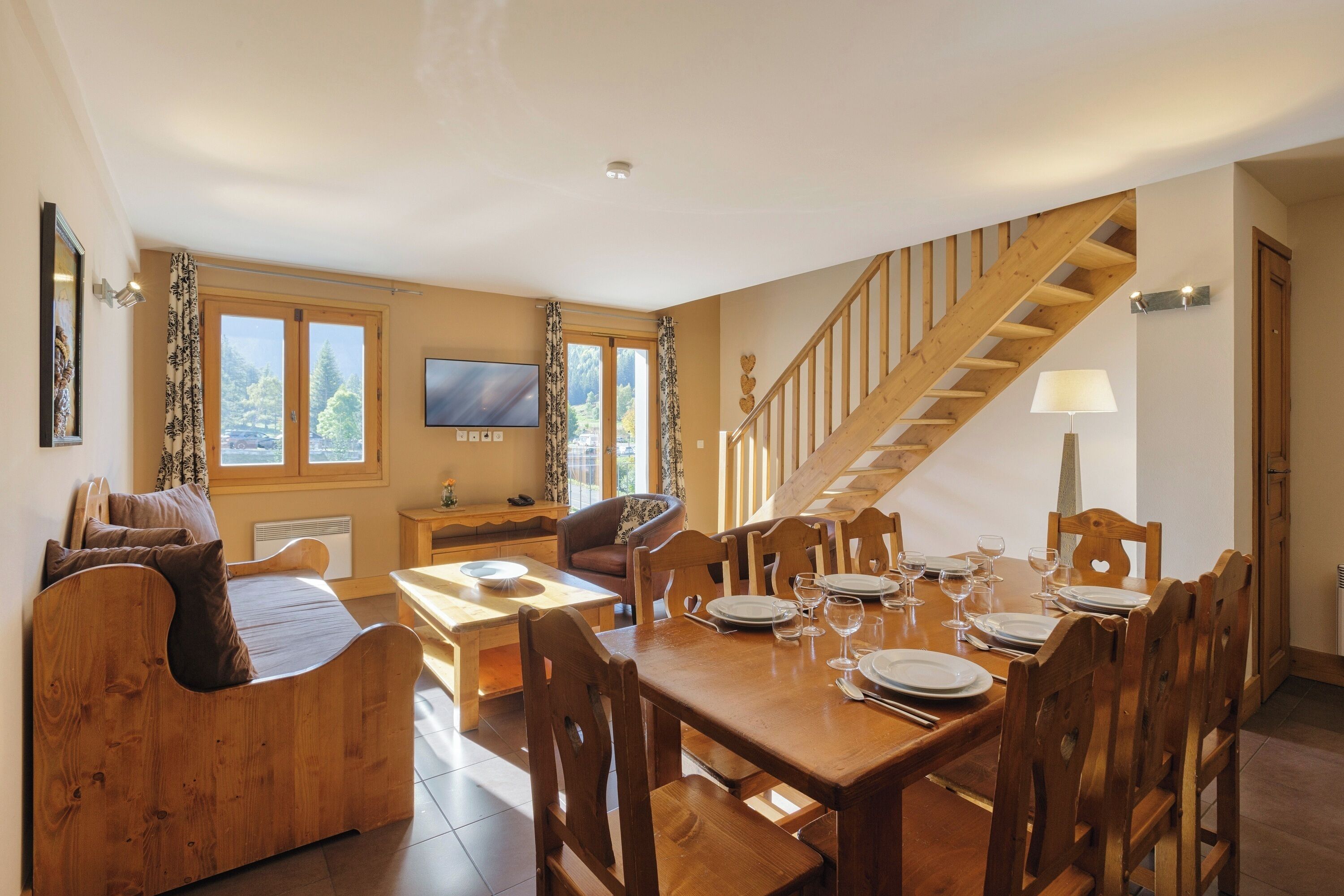 A dining area with wooden furniture, a TV, and a staircase.
