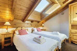 A room with two beds, wooden ceiling beams, a skylight, and a wooden cabinet. - Vallorcine Apartments (Vallorcine)