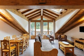 A wooden interior with a dining area, seating, and a view through large windows. - Vallorcine Apartments (Vallorcine)