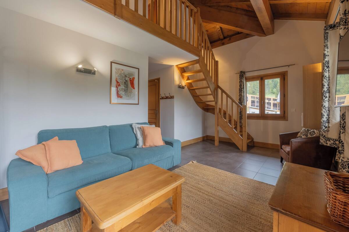 Un salon avec un canapé bleu, une table basse en bois et un escalier.