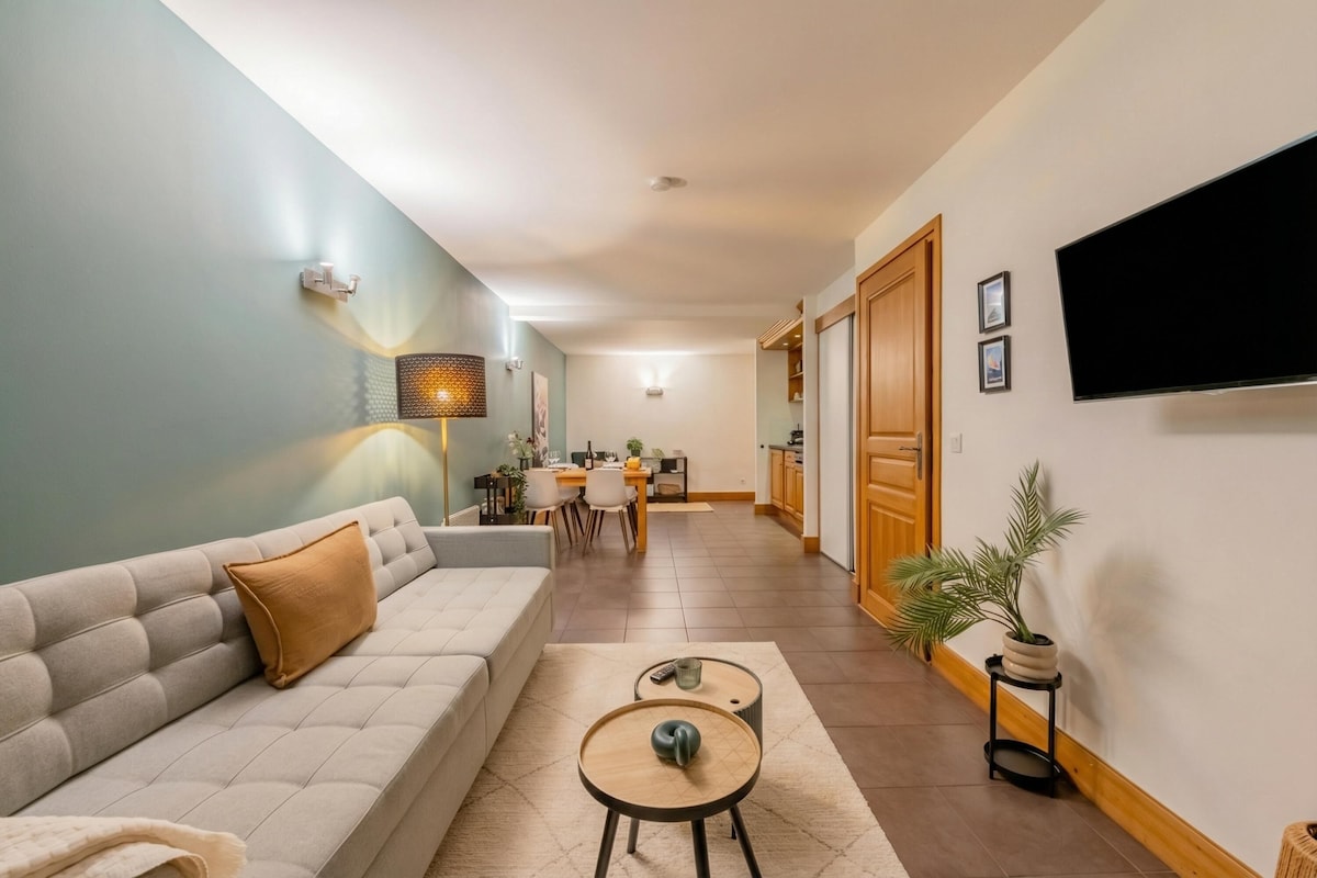 Una sala de estar moderna con un sofá, una mesa de centro y un televisor montado en la pared.
