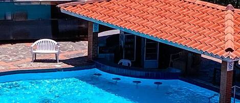 Ein Pool mit Flachdach, Liegestühlen und einer Wandmalerei zum Thema Meer.