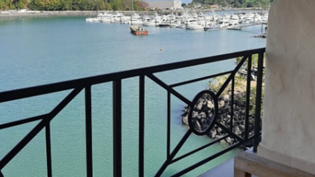 A balcony with a view of a marina and a hilly landscape. - The Beach House (Panama City)
