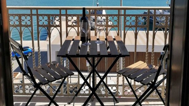 A balcony with a view of the sea, a table with chairs, and a railing. - B&b Belveliero (Trapani)