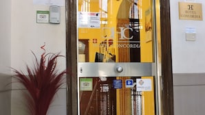 A hotel entrance with a glass door, a TripAdvisor badge, and a sign indicating a 4+ rating. - Hotel Concordia (Palermo)