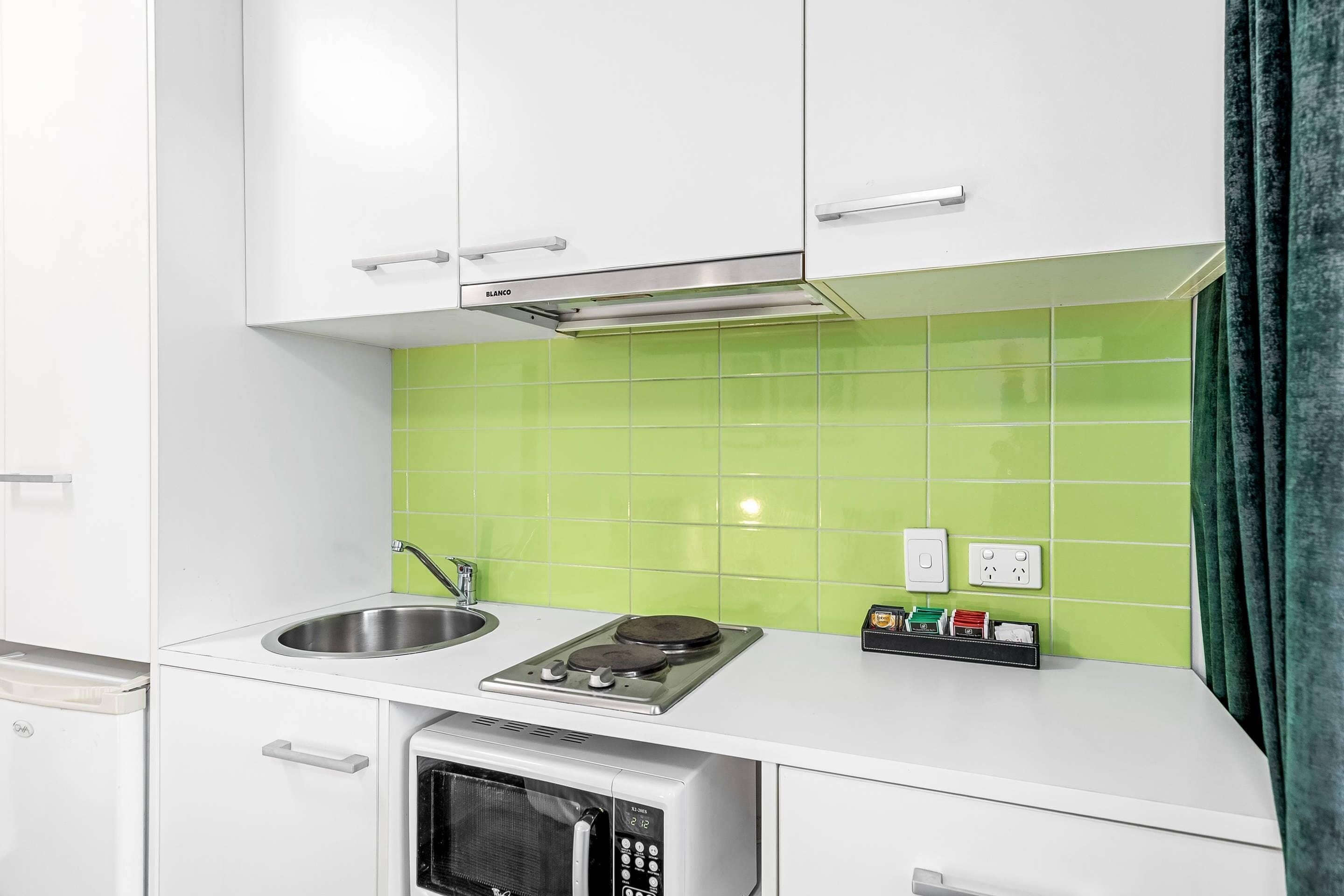 A kitchen with white cabinets, a stainless steel sink, a microwave, and a gas stove.