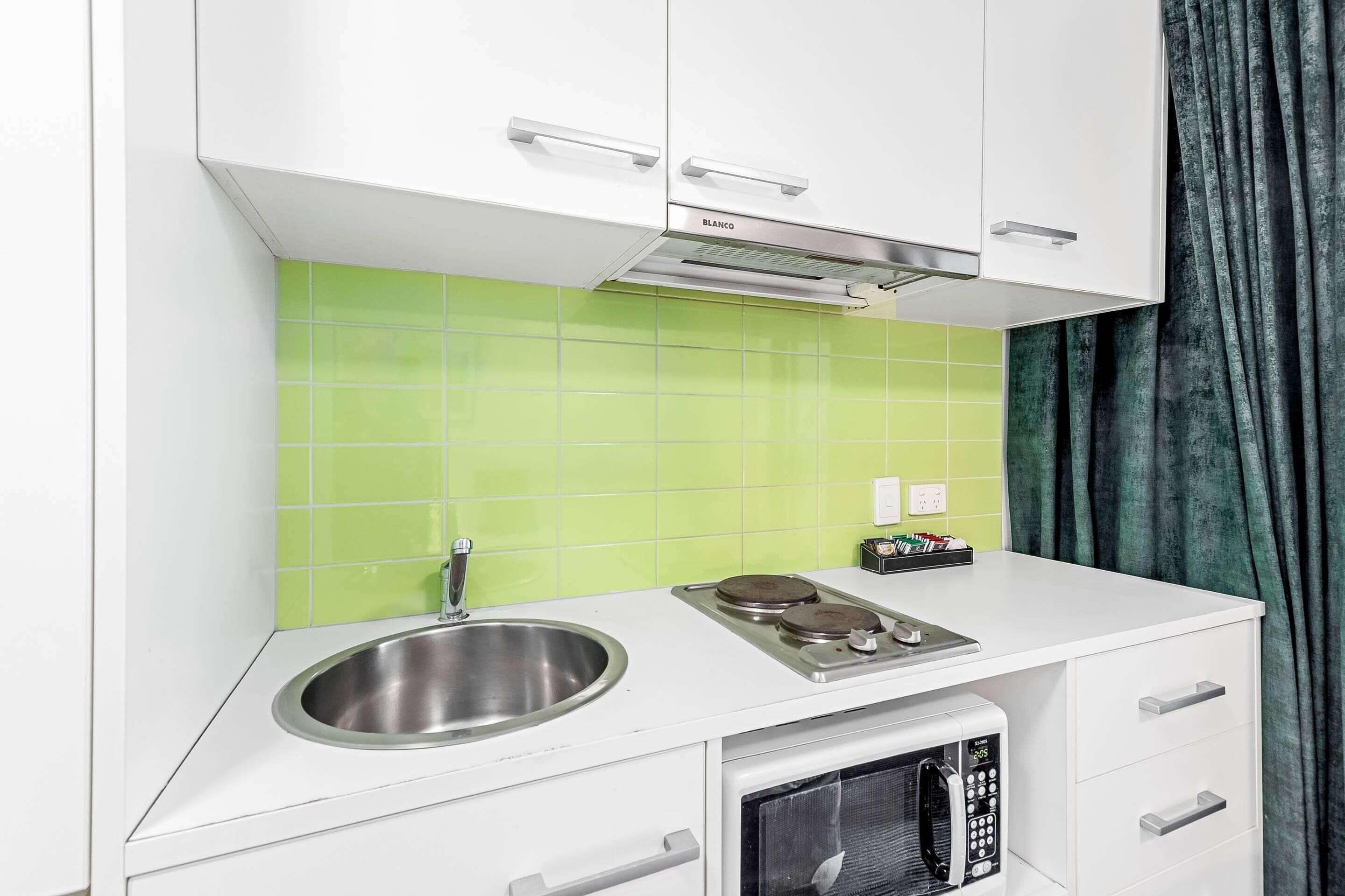 Una kitchenette compacta con pileta, estufa y microondas.