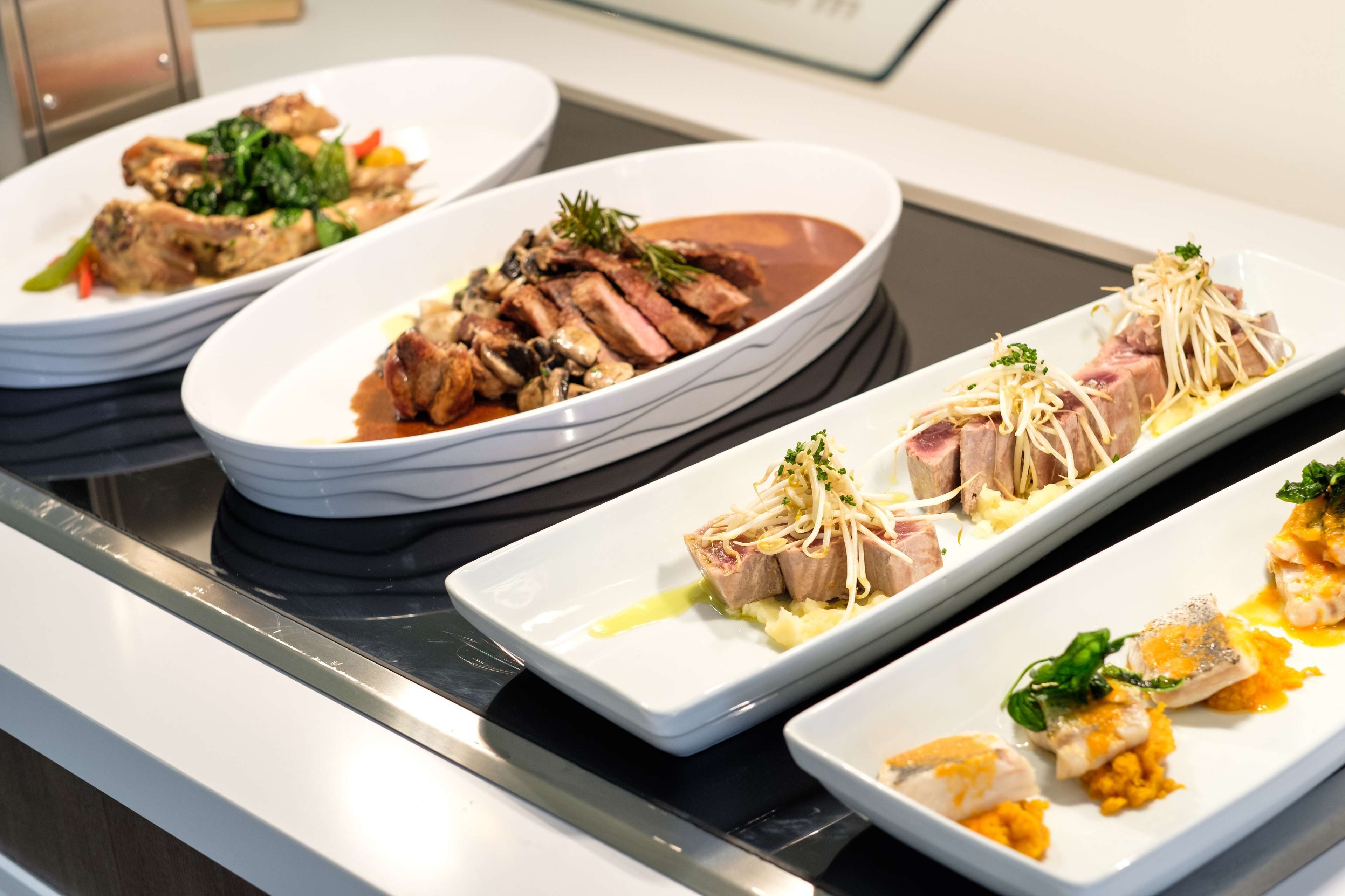 Un bufé con diversos platos, incluyendo carnes y verduras.