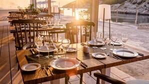Une table dressée pour le dîner, avec vue sur un plan d’eau et des collines en arrière-plan.