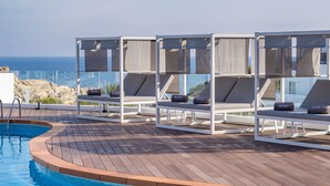 Un espace aménagé au bord de la piscine, avec des chaises longues et une vue sur l’océan.
