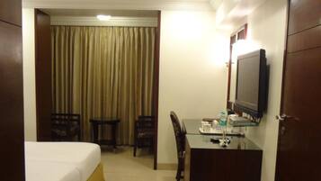 A hotel room with a bed, a desk, a chair, a television, and a curtain.