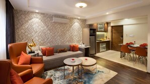 A modern living room with a sofa, armchairs, and a dining area with chairs and a table. - Hotel Suba Palace (Mumbai)