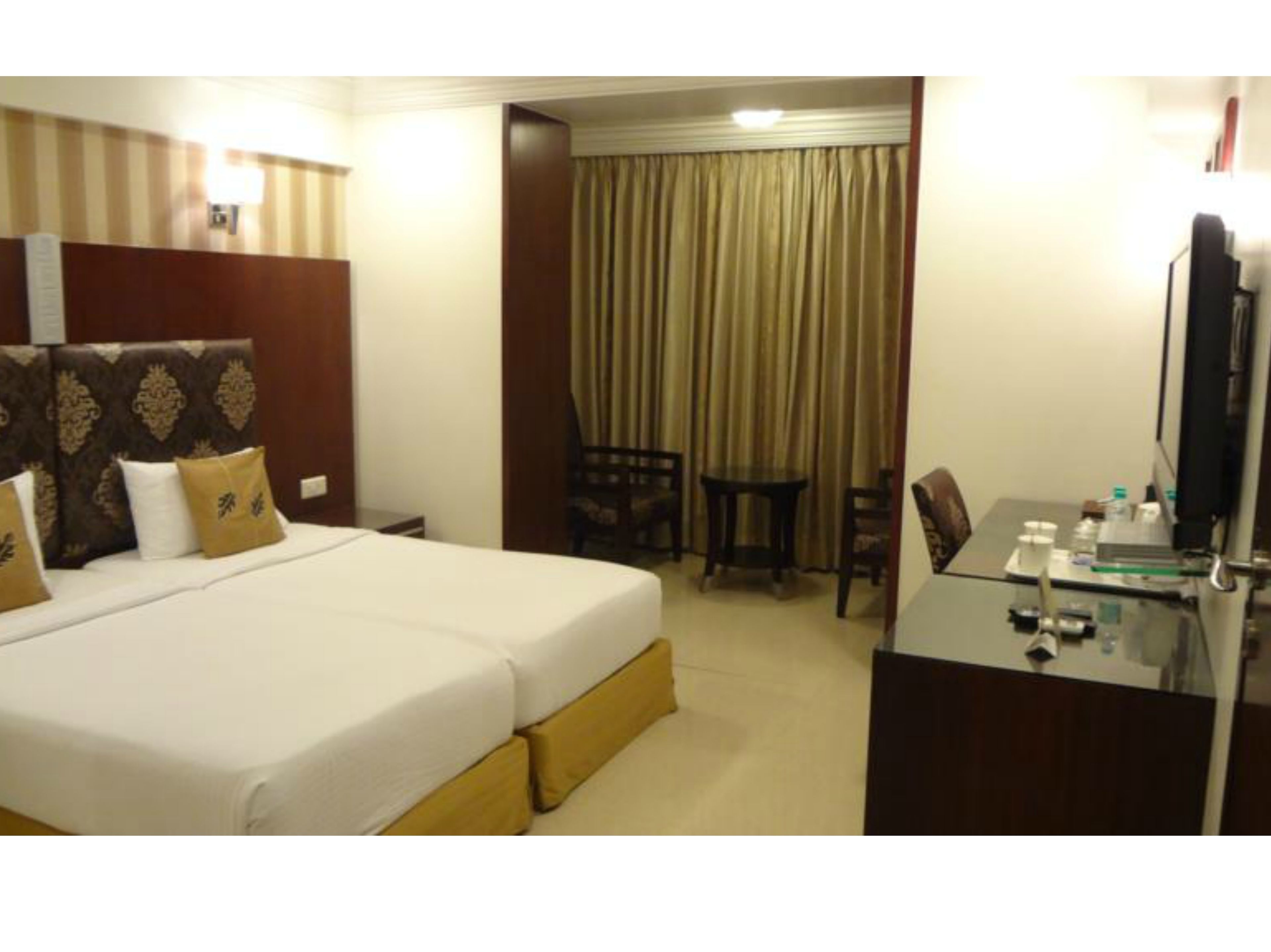 A hotel room with a large bed, a desk with a computer, a chair, and a table.