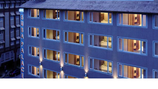 A multi-story hotel with a prominent 'SUBAPALACE' sign, featuring a modern facade and multiple illuminated windows suggesting interior lighting. - Hotel Suba Palace (Mumbai)
