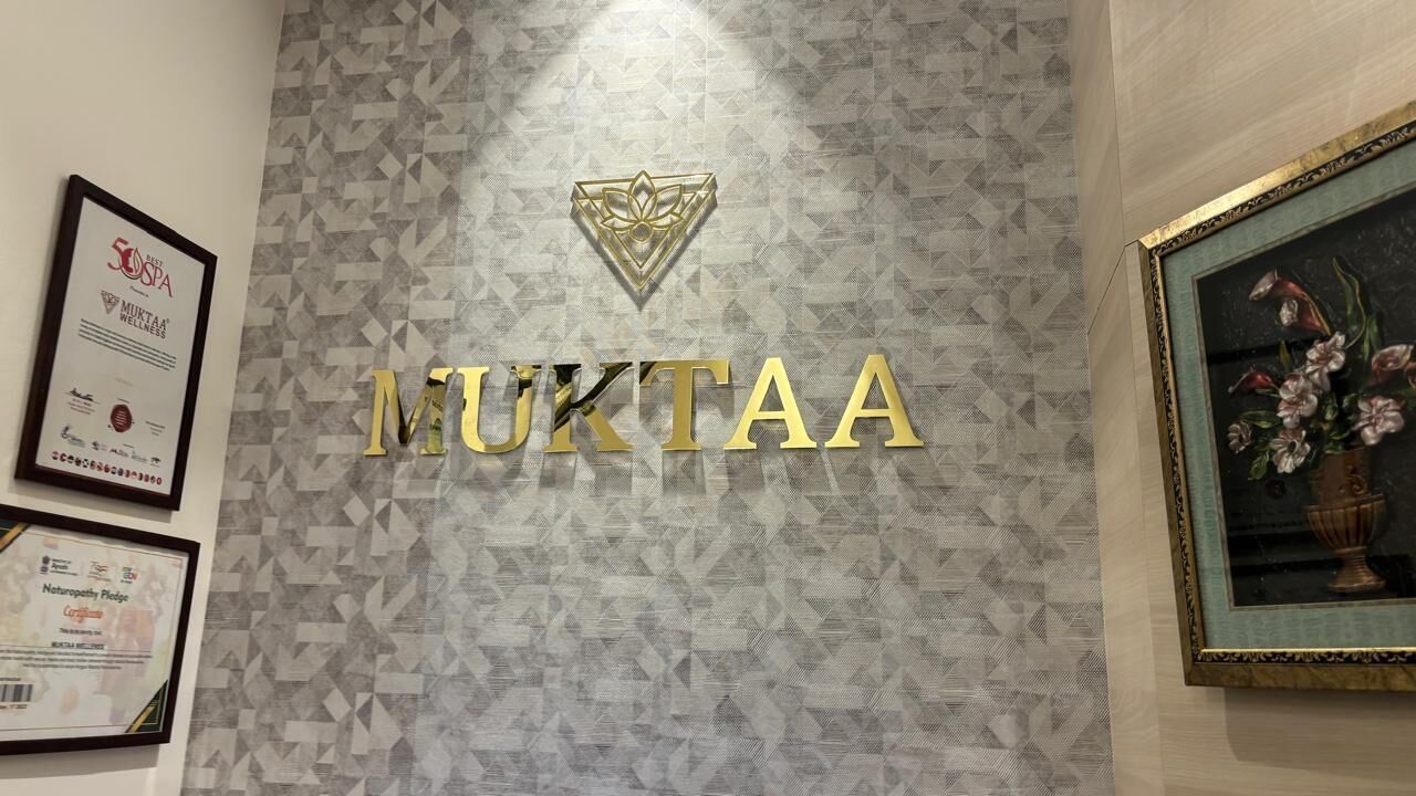 A wall with the name 'MUKTAA' in gold letters, a geometric patterned wall, and framed certificates.