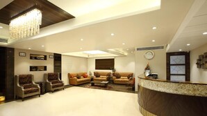 A spacious lobby with a reception desk, sofas, armchairs, and a chandelier. - Hotel Suba Palace (Mumbai)