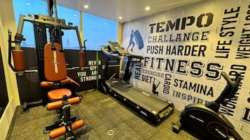 A gym with cardio equipment, a weight bench, and motivational wall art.