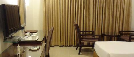 A hotel room with a bed, a desk with a computer, a chair, and a television.