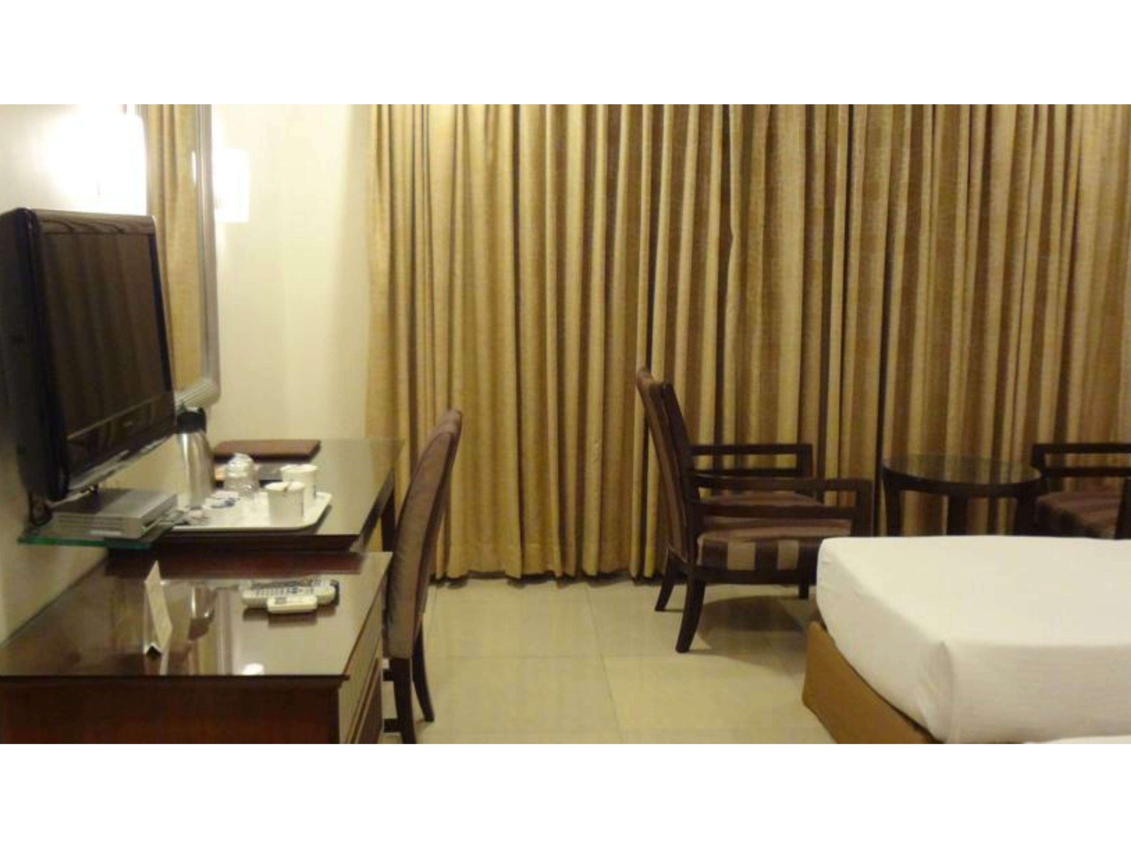Une chambre d’hôtel comprenant un lit, un bureau avec une télévision, une chaise et une petite table.