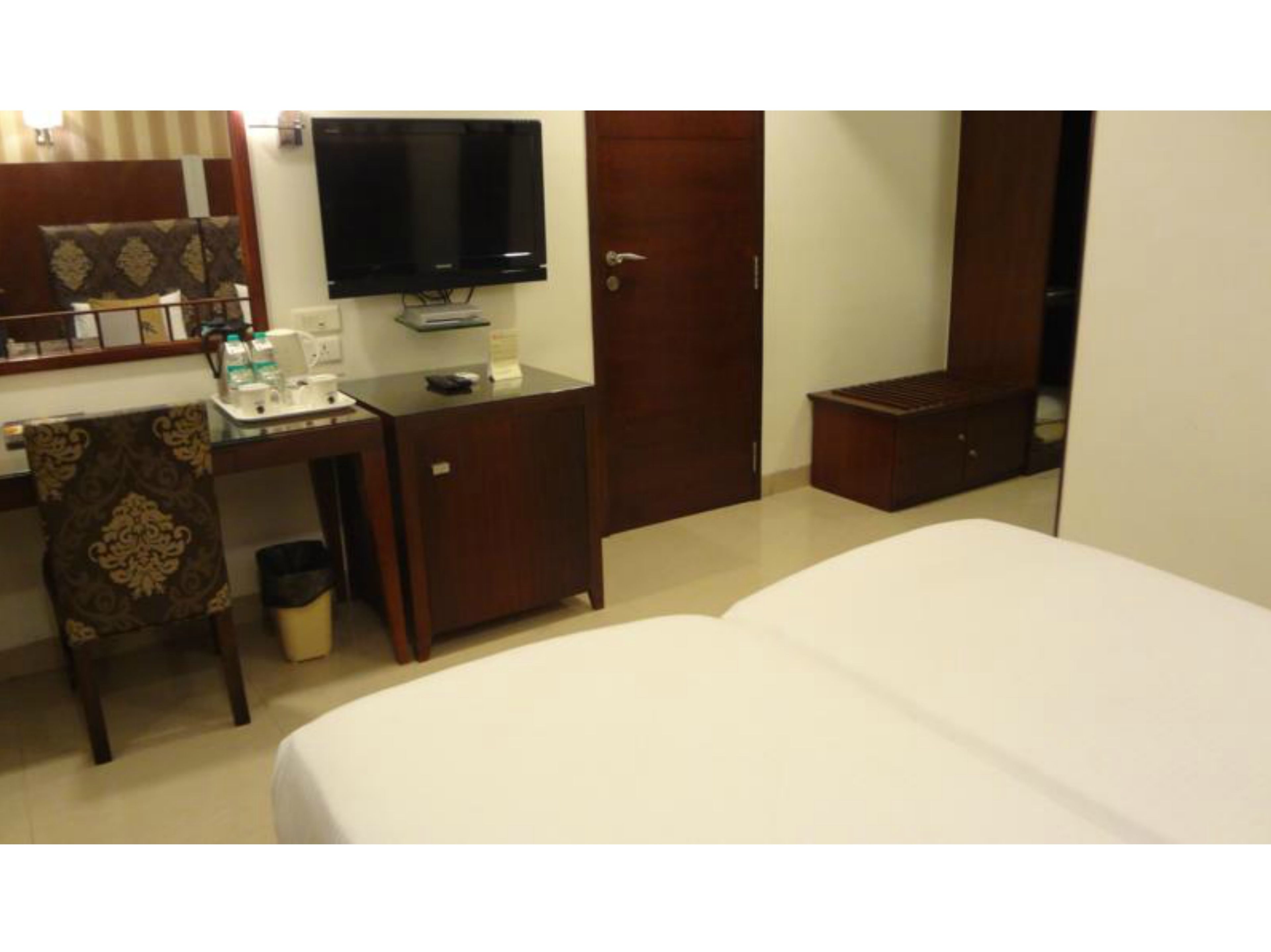 Habitación de hotel con cama, escritorio, computadora, televisor y armario.