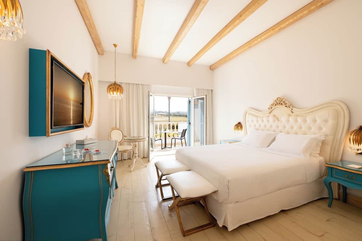 Un dormitorio con una cama grande, televisión, escritorio y balcón con vistas.