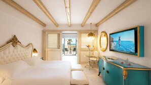 Ein Schlafzimmer mit Bett, Schreibtisch, Stuhl, Kommode, Fernseher und einem Balkon mit Meerblick.