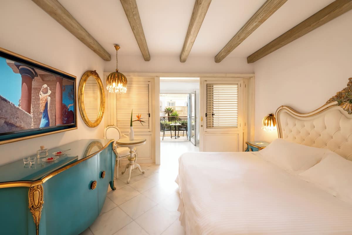 Un dormitorio con una cama, un tocador, un espejo y un cuadro en la pared.