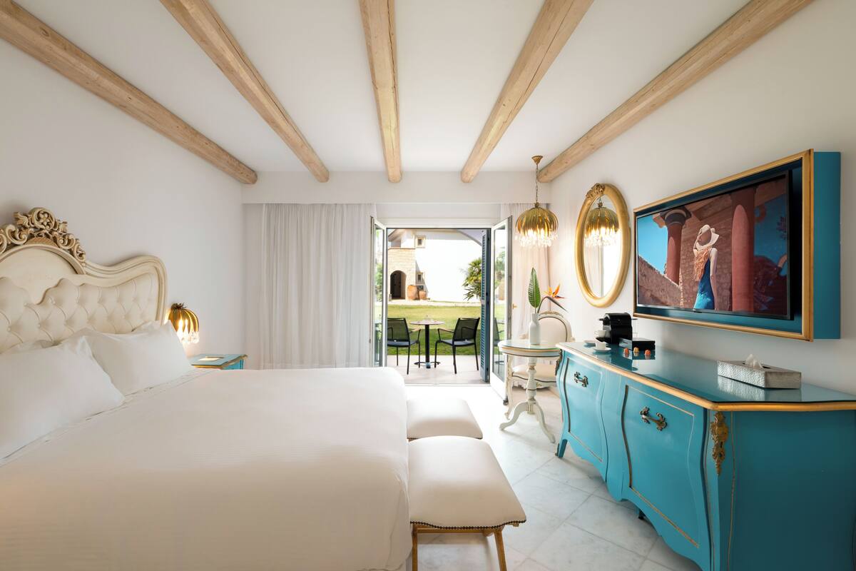Un dormitorio con una cama grande, un tocador con espejo y un televisor.