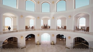 Ein mehrgeschossiges Atrium mit Bogenfenstern, einem zentralen Innenhof und einer Treppe.