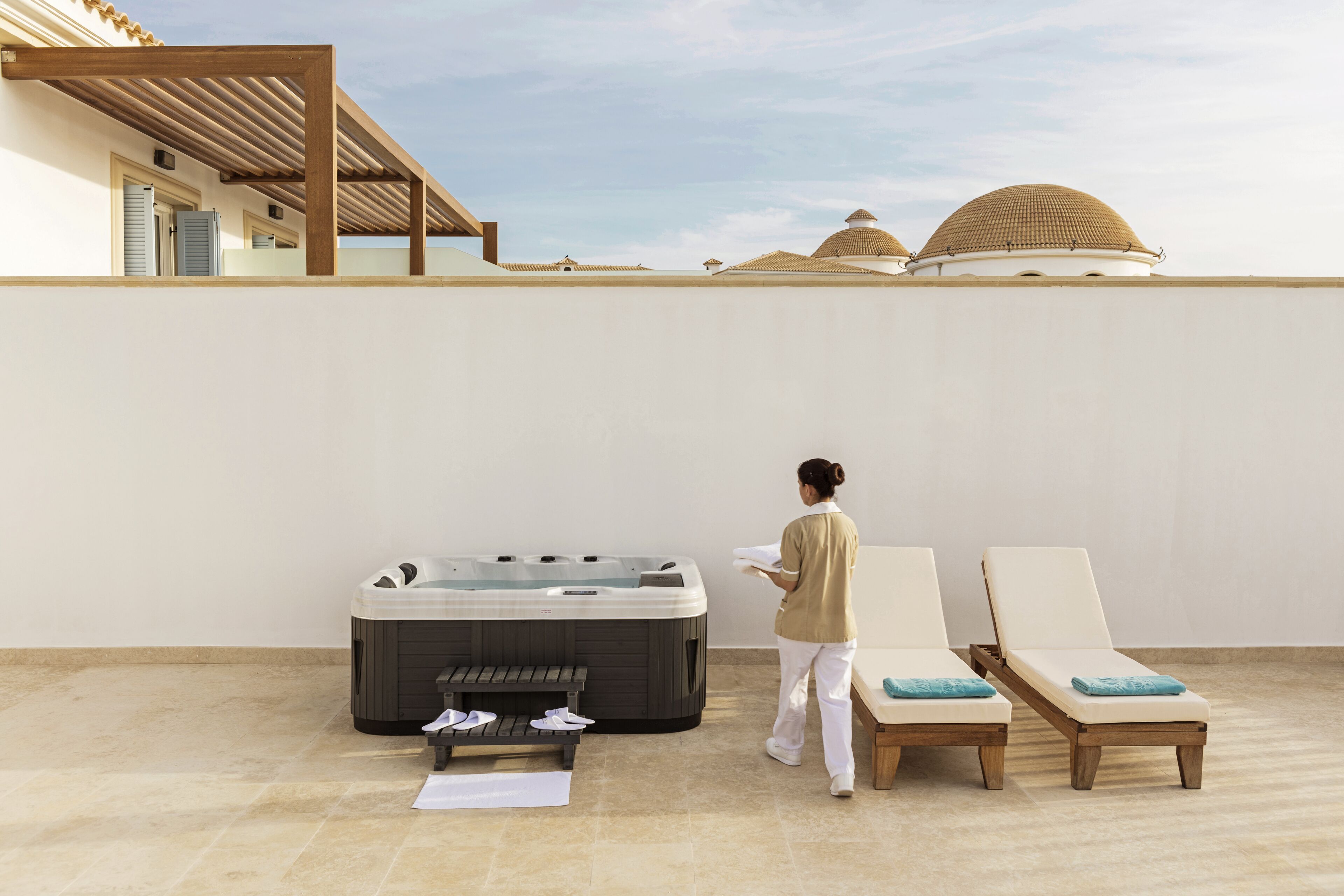 Terraza en la azotea con jacuzzi, sillas de descanso y una pérgola.