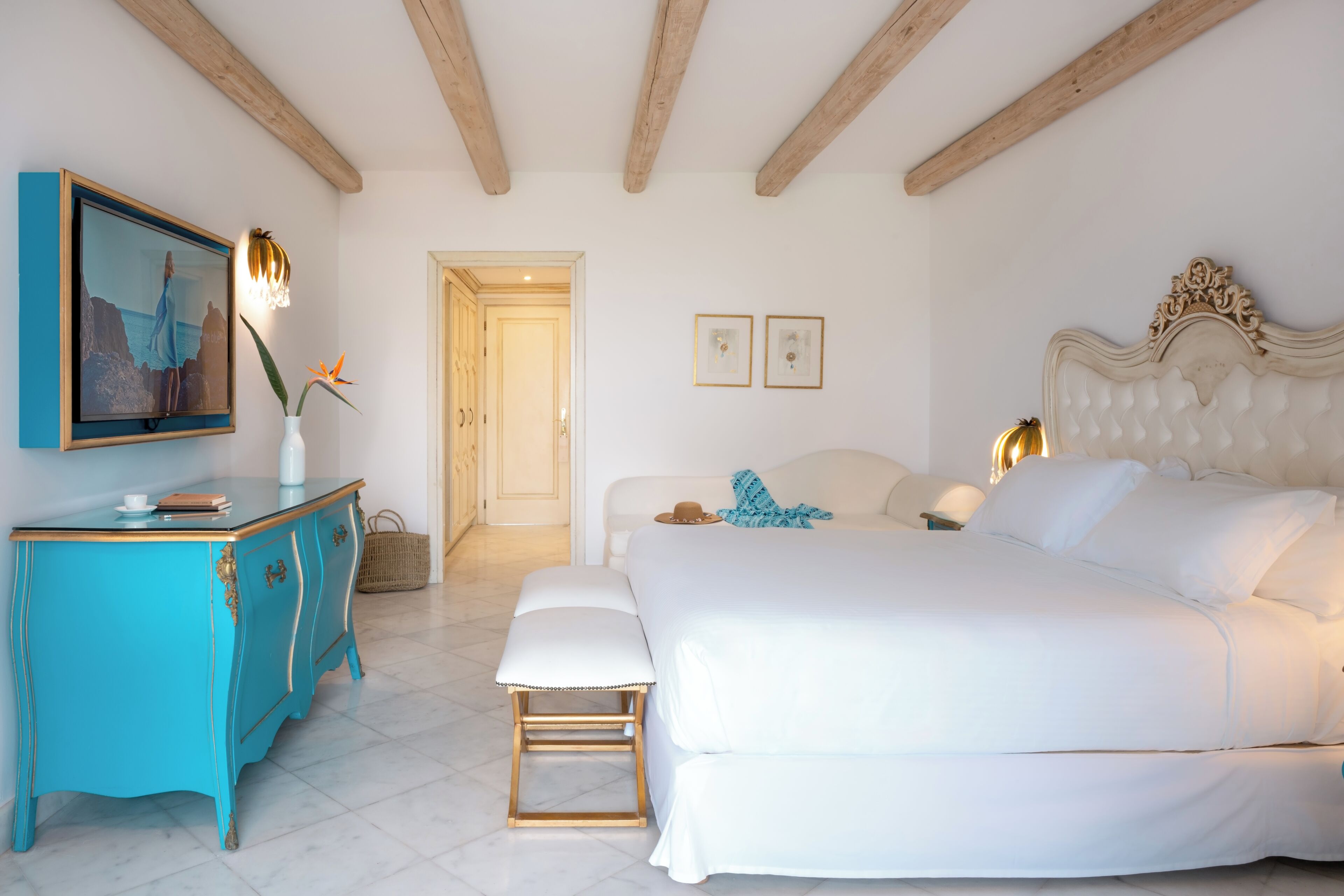 Un dormitorio con cama, cómoda, banco y puerta.