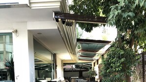 An outdoor patio area with wicker furniture, potted plants, and a wooden deck. - Riva Resatbey Hotel (Adana)