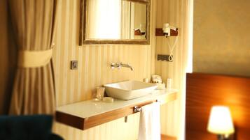 A hotel bathroom with a large mirror, a sink, a towel, and a lamp.
