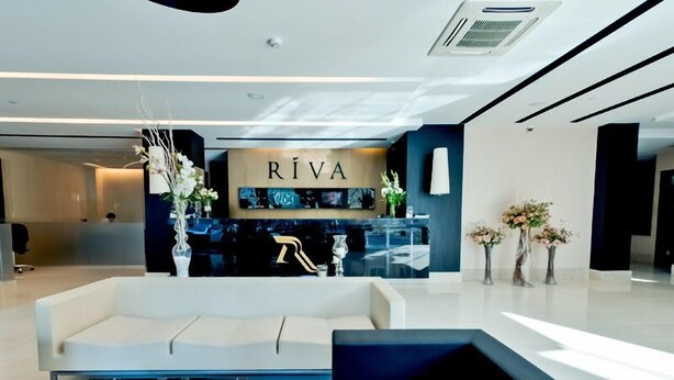 A modern lobby with a reception desk, sofas, and a coffee table with magazines. - Riva Resatbey Hotel (Adana)