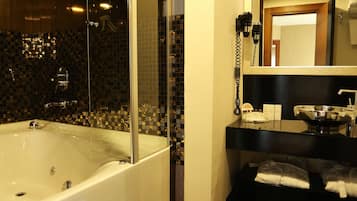 Un baño moderno con ducha de vidrio, una bañera grande y piso de baldosas negras.