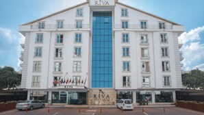 A multi-story hotel with a prominent blue glass facade, multiple balconies, and a sign reading "RIVA." - Riva Resatbey Hotel (Adana)