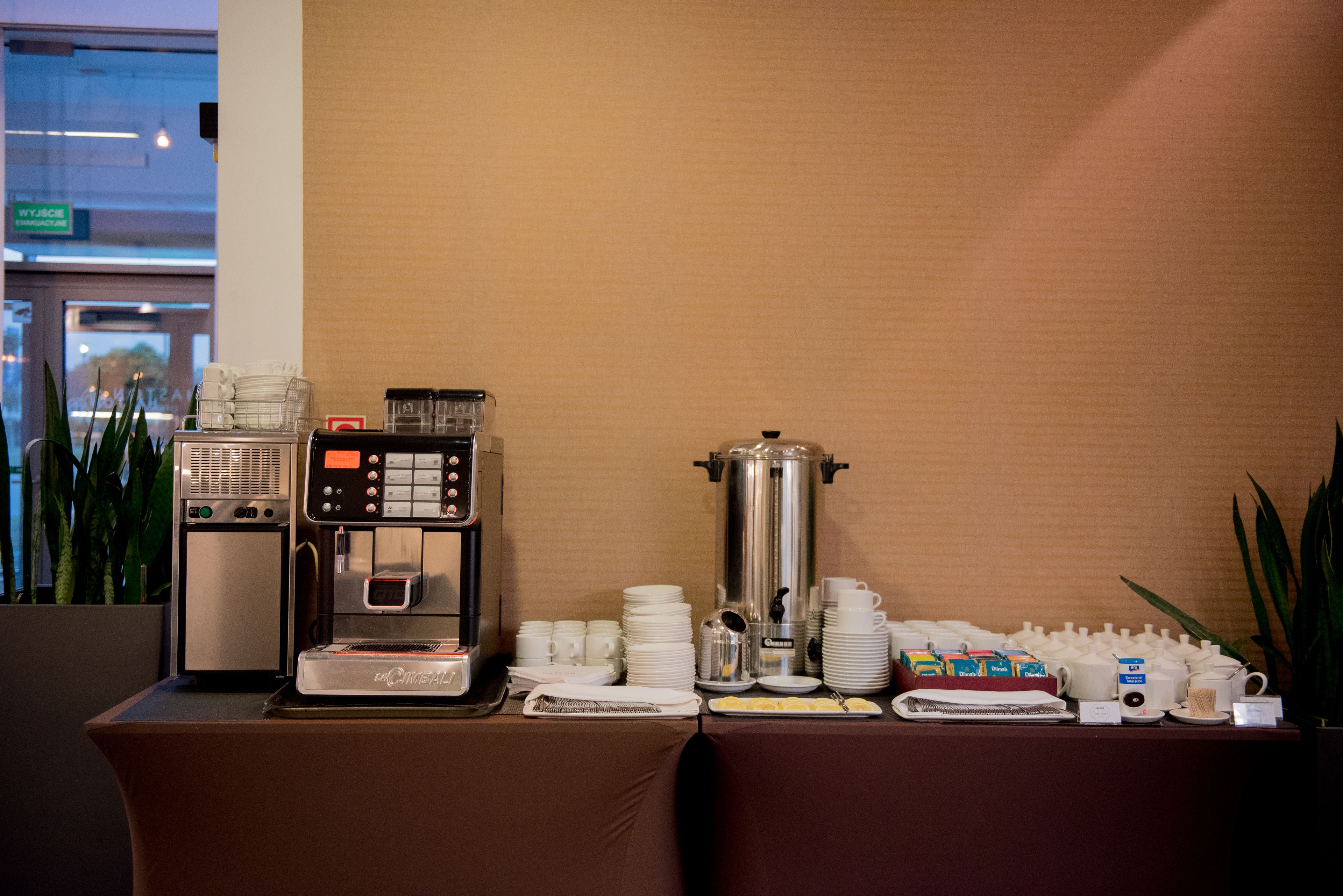 Un buffet avec des machines à café, des assiettes et des couverts.