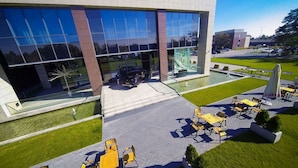A modern building with large glass windows, outdoor seating area, and a small water feature. - Haston City Hotel (Wroclaw)