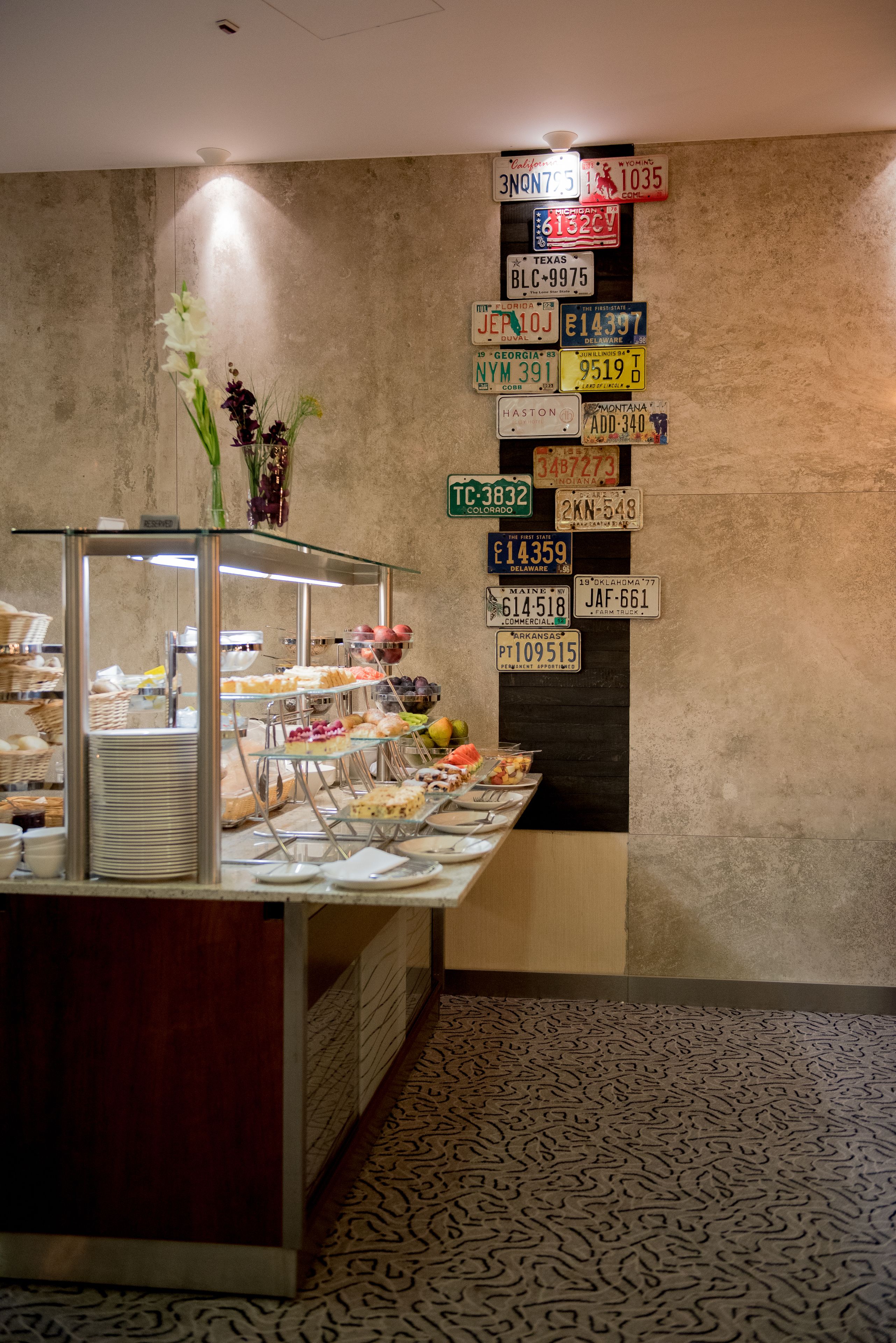 Zona de bufé con diferentes alimentos y una pared que muestra varias placas de matrícula.