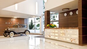 A modern hotel lobby with a vintage car, a reception desk, and clocks indicating different time zones. - Haston City Hotel (Wroclaw)