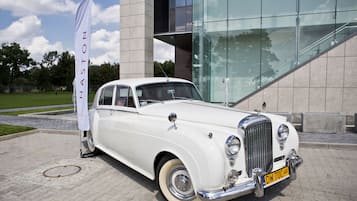 Un'auto bianca d'epoca parcheggiata di fronte a un edificio moderno con facciata in vetro.