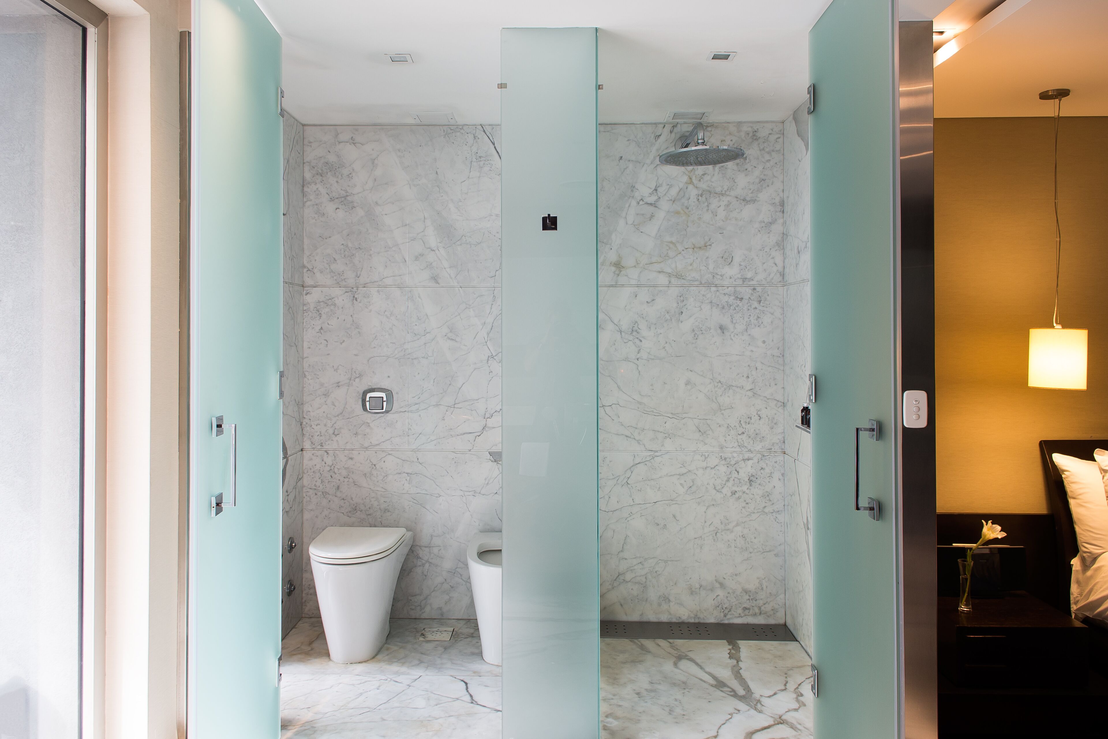 Een moderne badkamer met een marmeren vloer, een douchecabine van glas en een toilet.