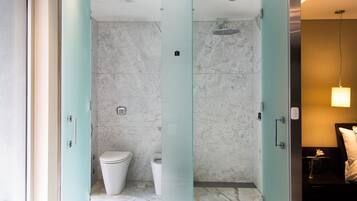 Een moderne badkamer met een marmeren vloer, een douchecabine van glas en een toilet.