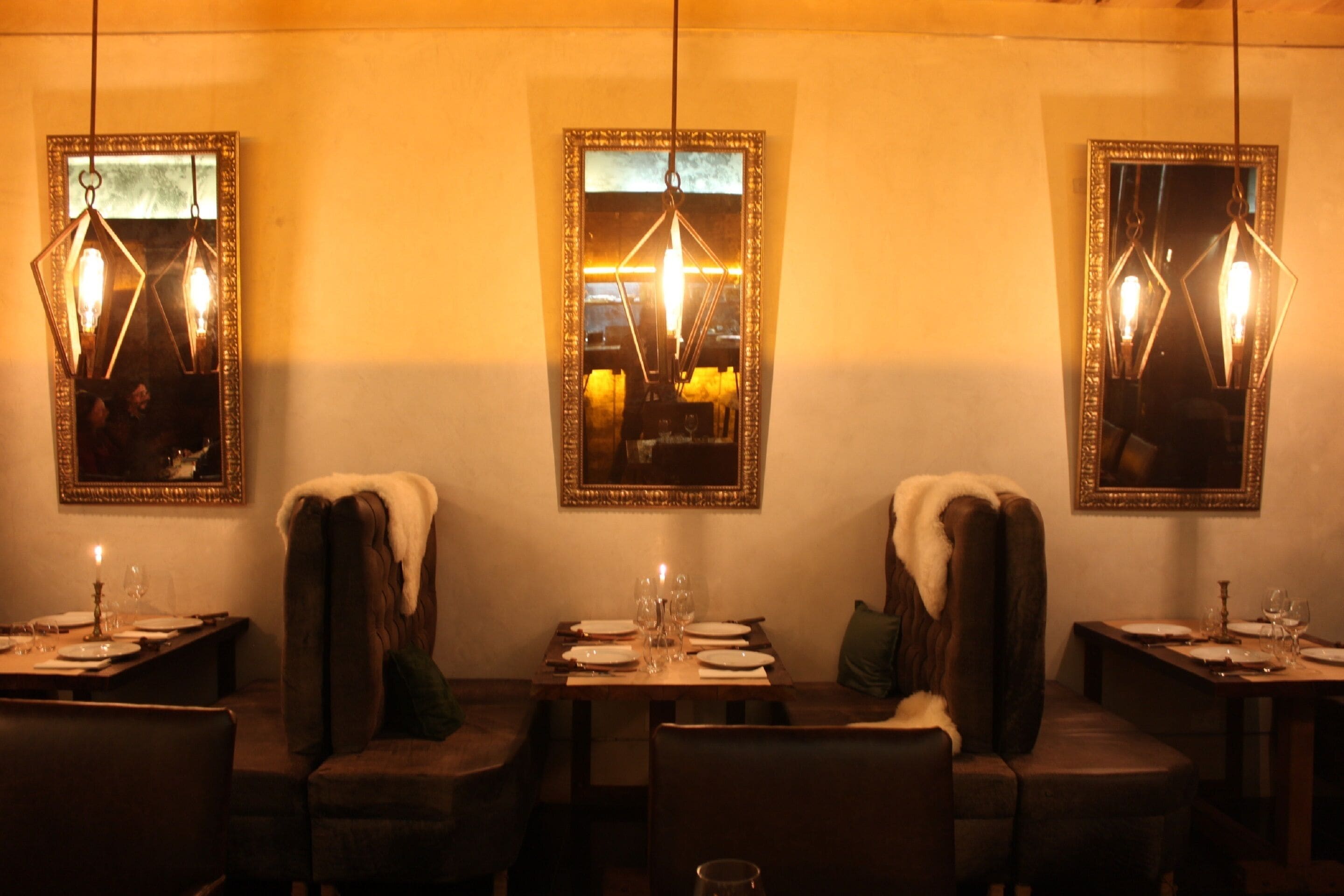 A dining area with tables set for two, each with a candle and wine glasses.