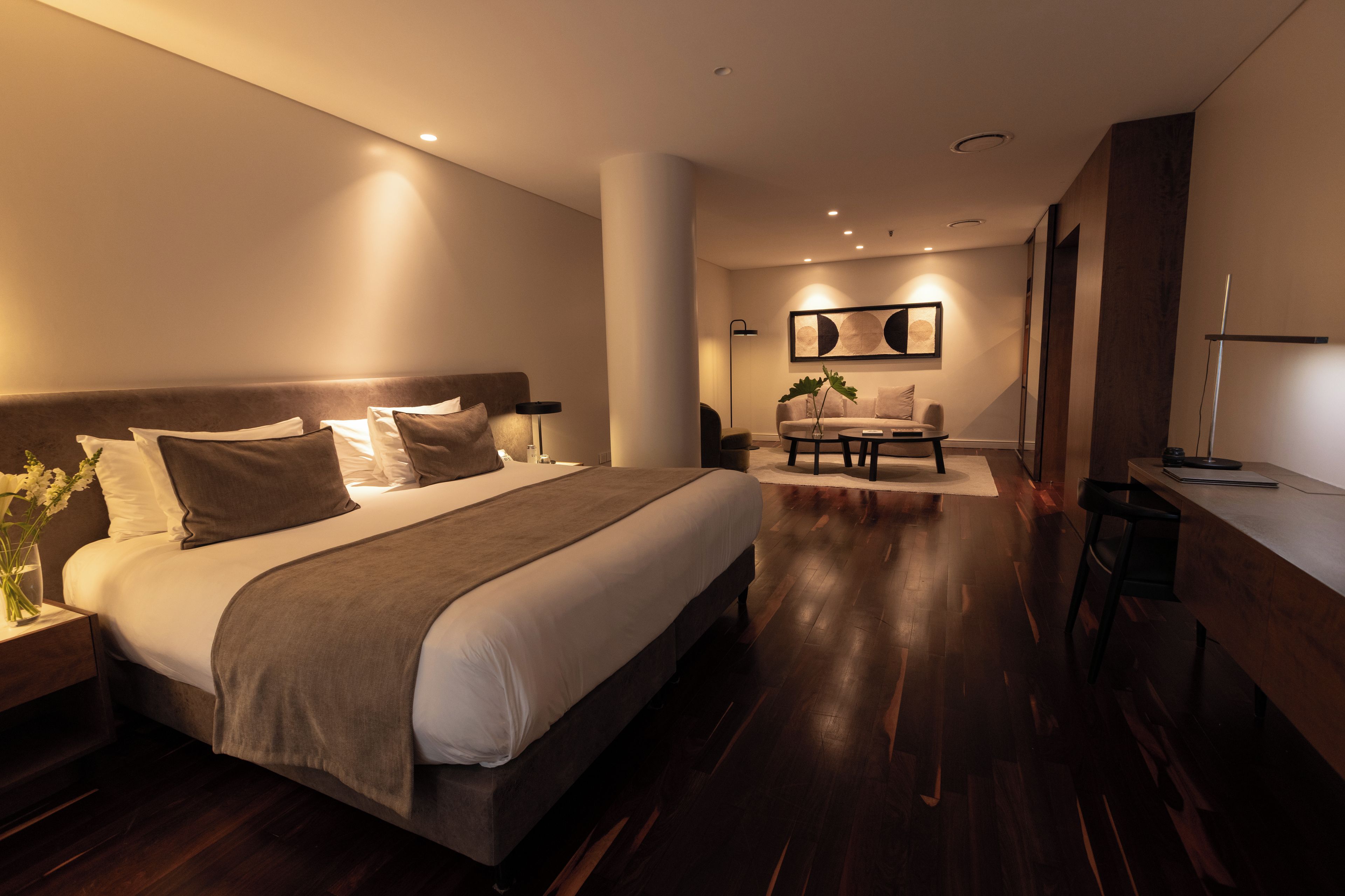 Quarto de hotel moderno com uma cama grande, uma escrivaninha e um espaço de estar.