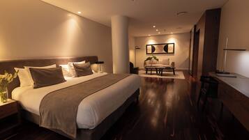 Quarto de hotel moderno com uma cama grande, uma escrivaninha e um espaço de estar.