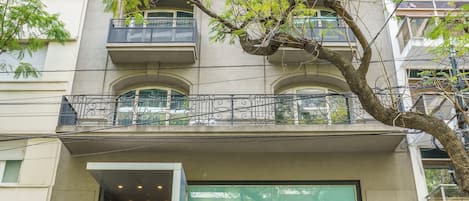 Un edificio de varios pisos con fachada moderna, ventanas grandes y balcones.