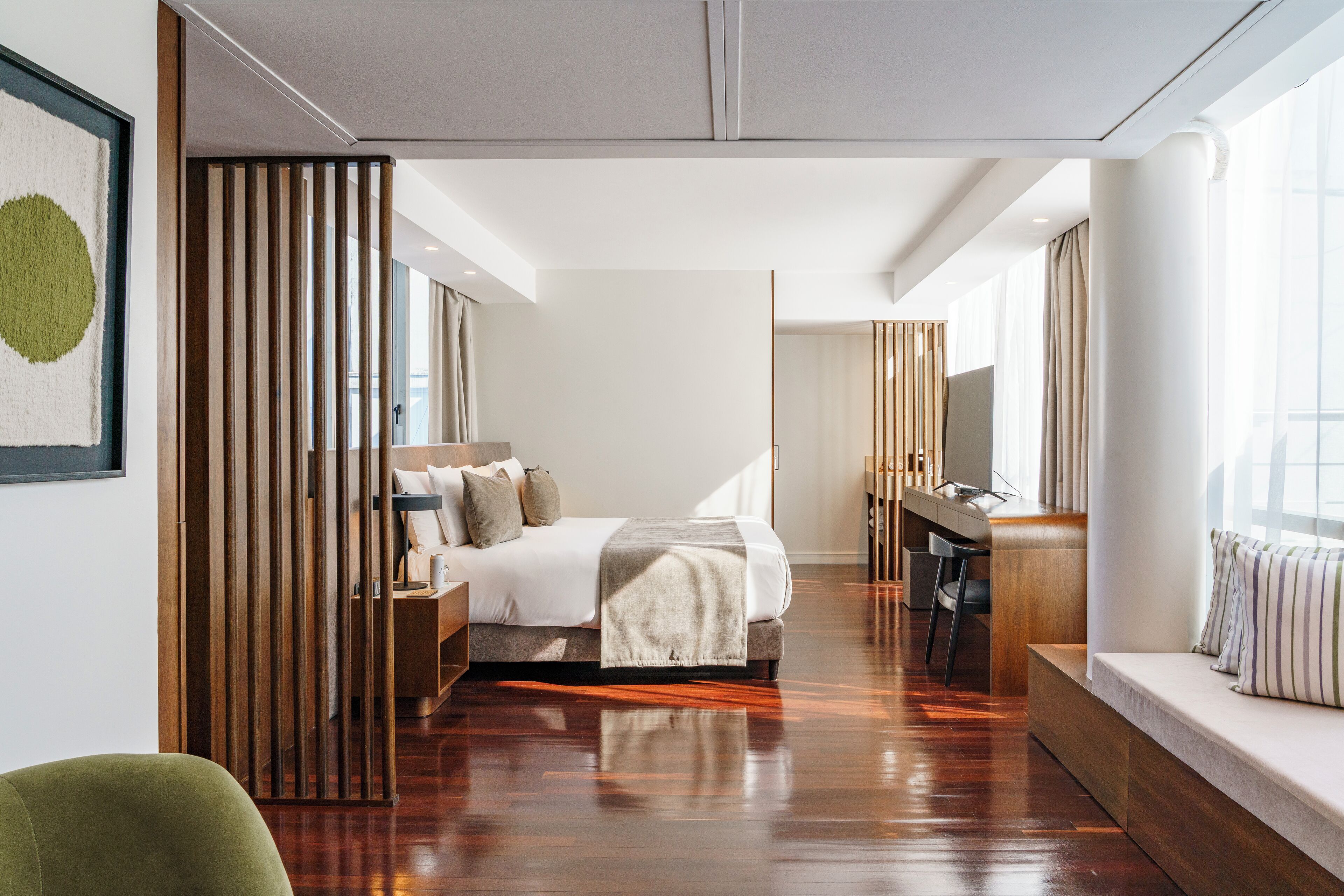 Una habitación de hotel moderna con una cama grande, un escritorio y una zona de estar junto a la ventana.
