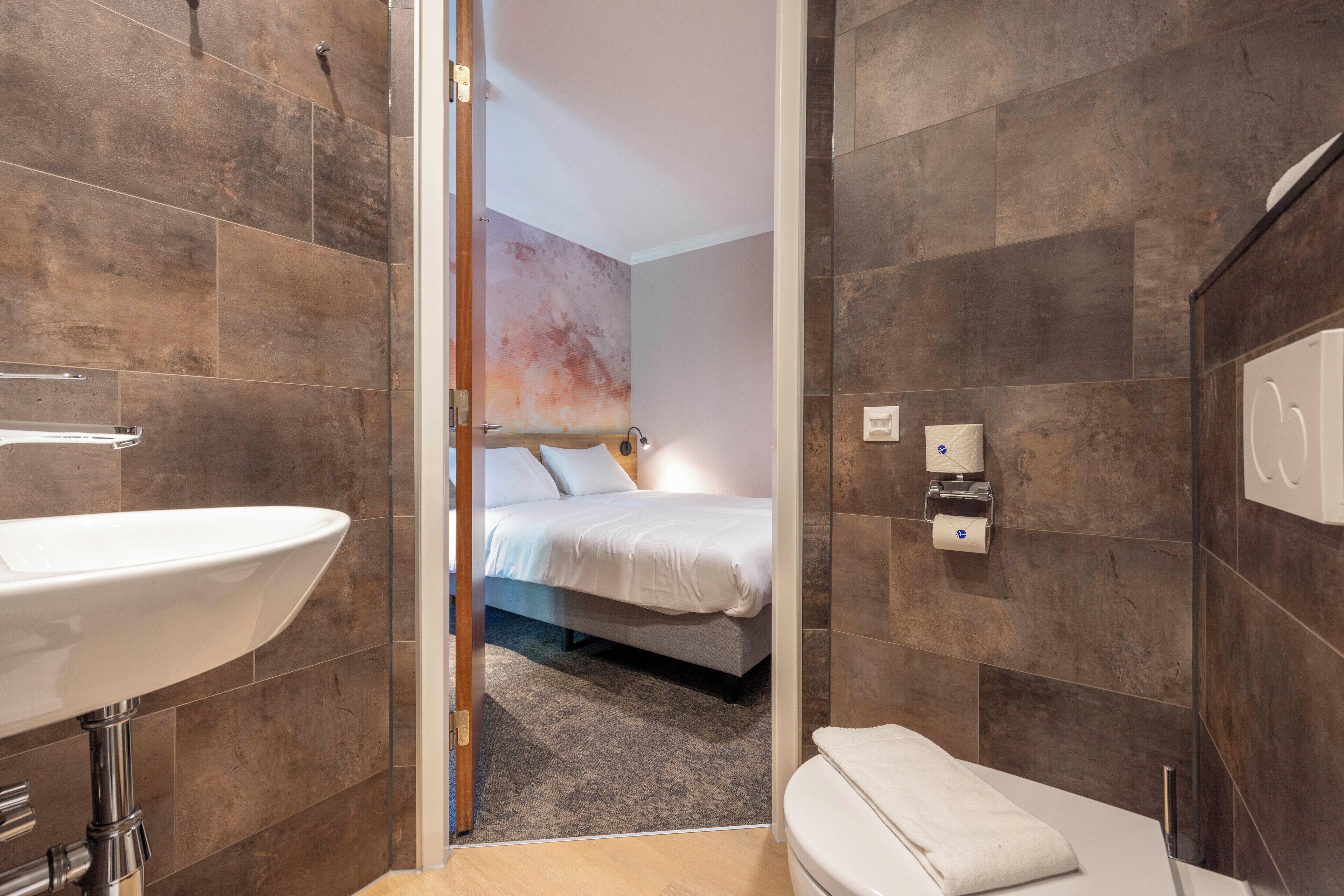 Een moderne badkamer met een groot wastafel, toilet en douchegedeelte.